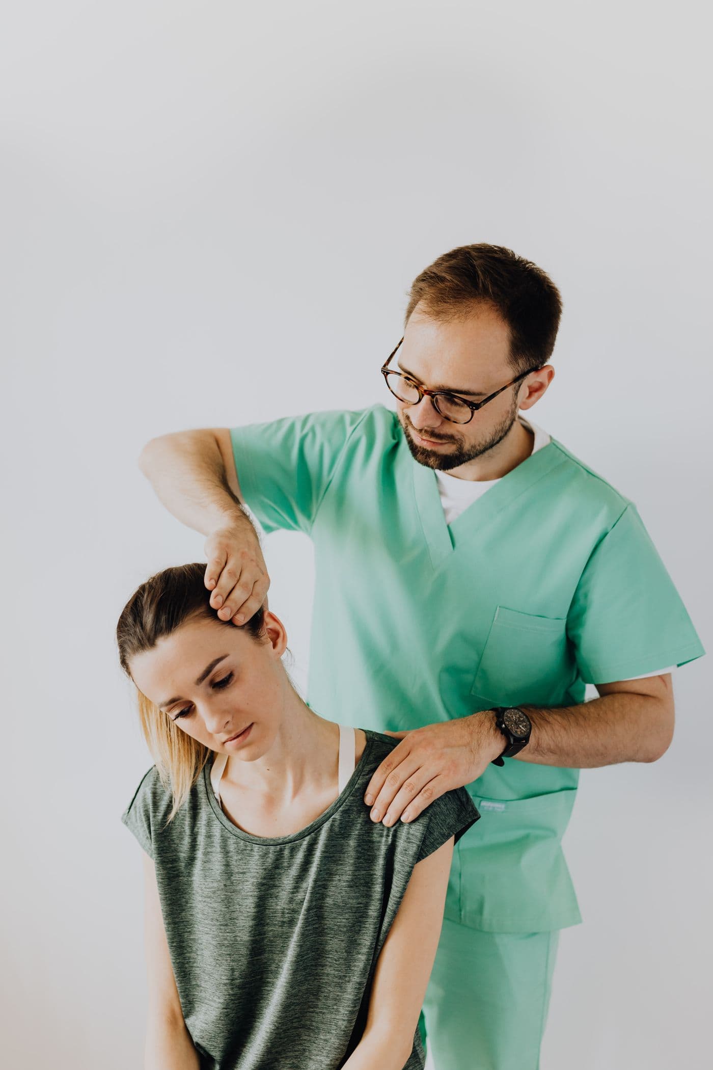 Kinesiólogo realizando tratamiento manual en el cuello de un paciente en consultorio